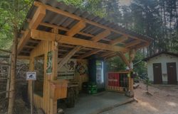 Überdachte Labstelle aus Holz mit Sitzgelegenheiten, Getränkekühlschrank und Zielscheibe am Bogenparcours im Naturpark Nordwald