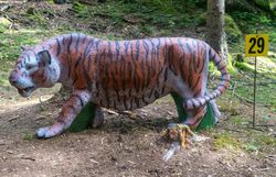 Gestreiftes 3D-Tigerziel in schleichender Haltung mit langem, gebogenem Schwanz auf einem Waldboden