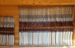 Zahlreiche nach Größe geordnete Bögen in einem Holzregal beim Bogenparcours