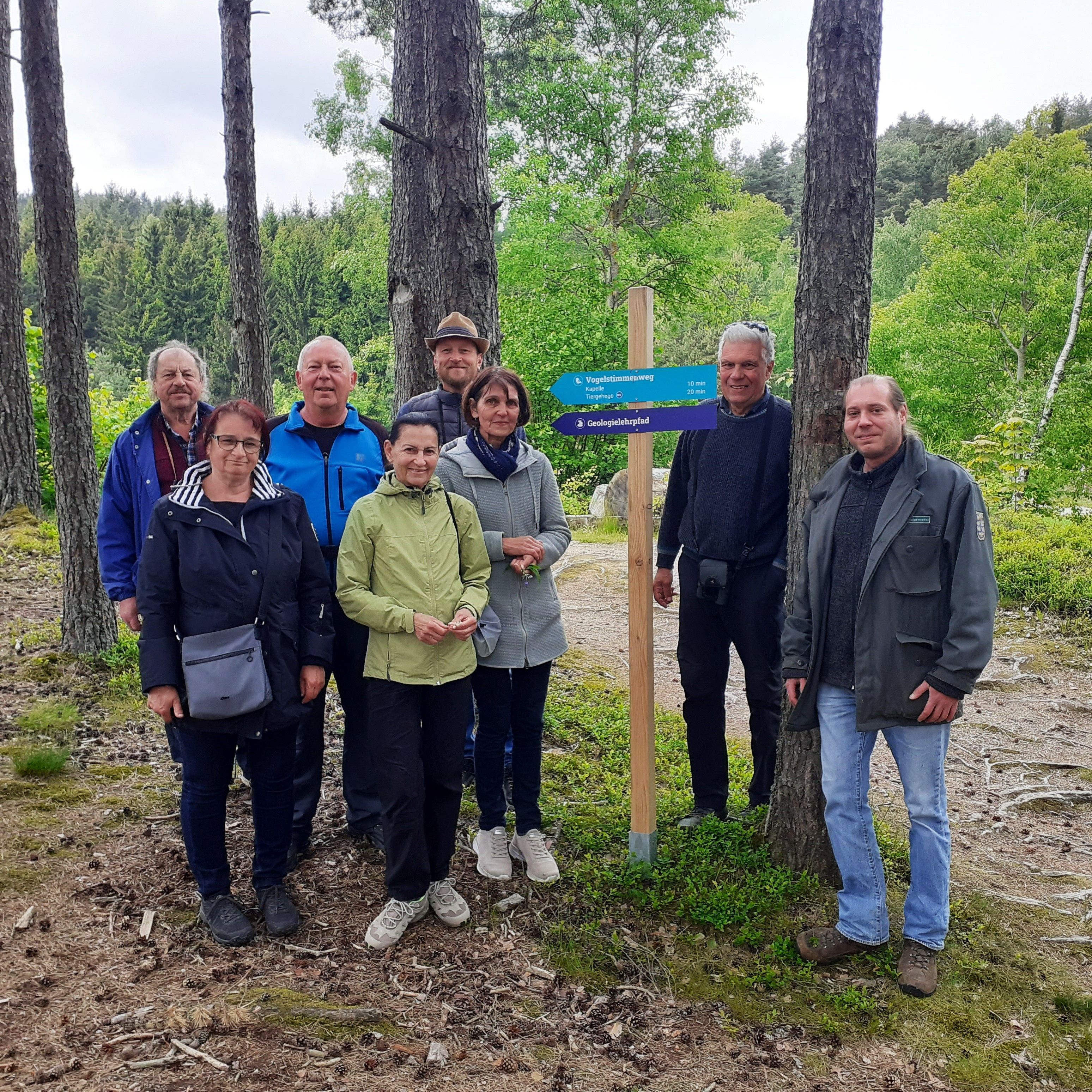 Teilnehmende einer naturkundlichen Exkursion bei einem Wegweiser im Naturpark Nordwald